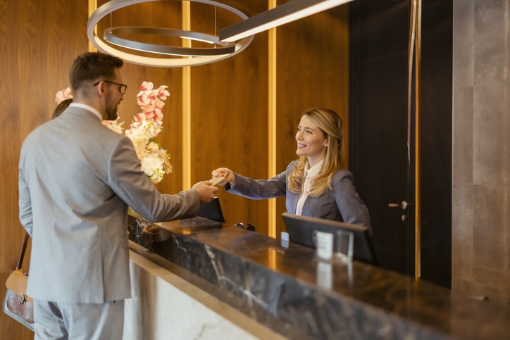 Female hotel receptionist assisting a business couple with check-in at a hotel, representing the excellent customer service provided by our staffing agency in Hackensack.
